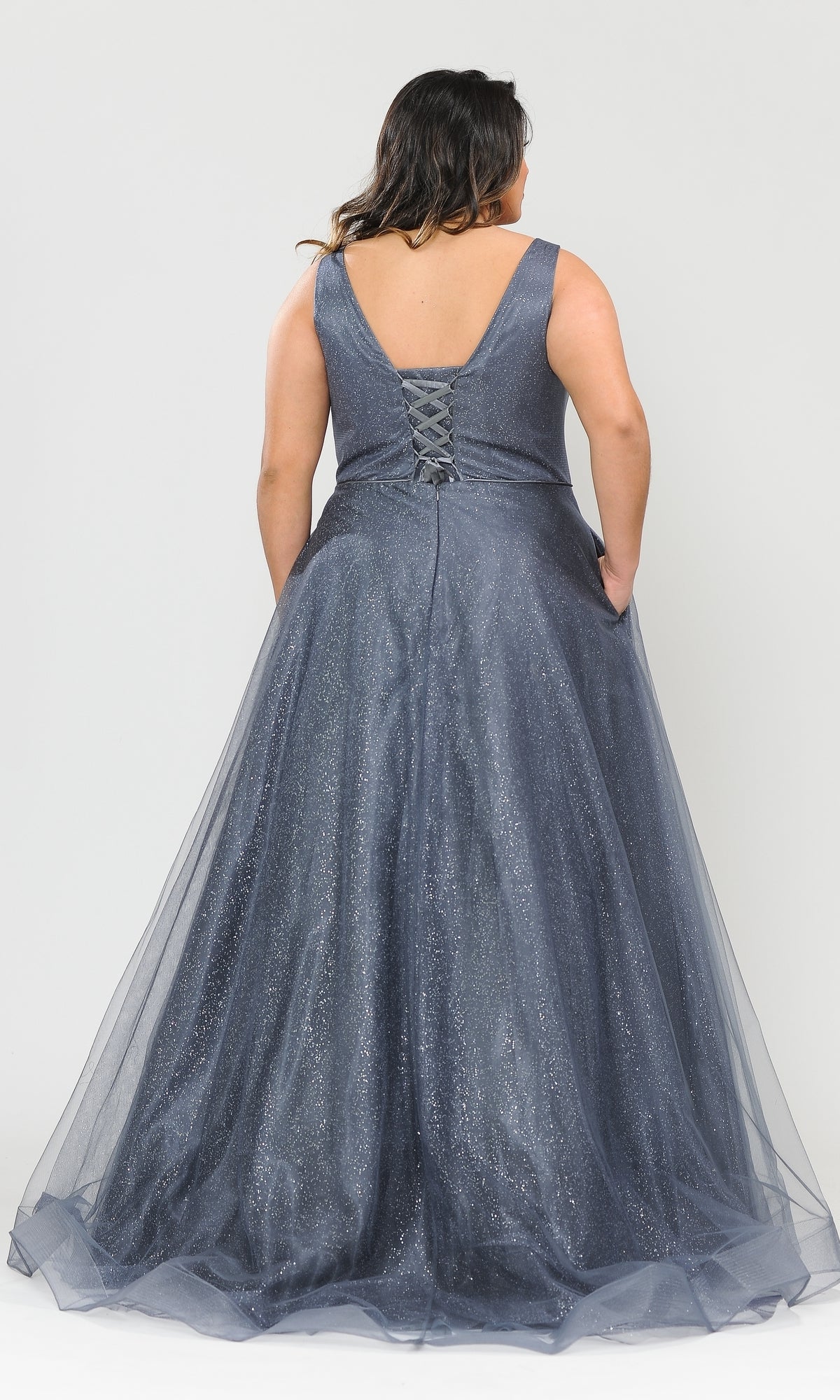 A woman models the Glitter-Tulle Plus-Size Long Prom Gown W1024, a sleeveless floor-length dress with V-back and lace-up detail, shown from behind against a plain background.